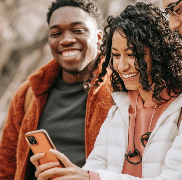 A couple of friends grinning wide and taking a selfie.